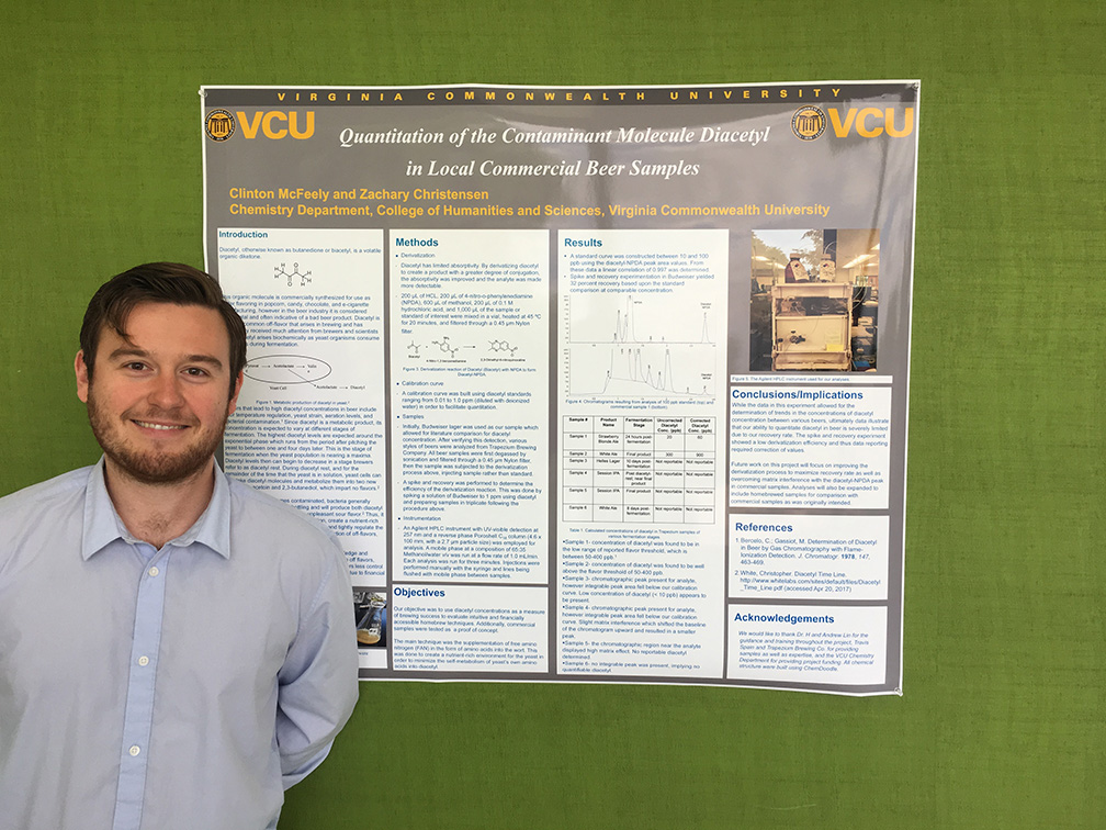 Clinton McFeely stands in front of a research poster presentation hanging up on a green backdrop