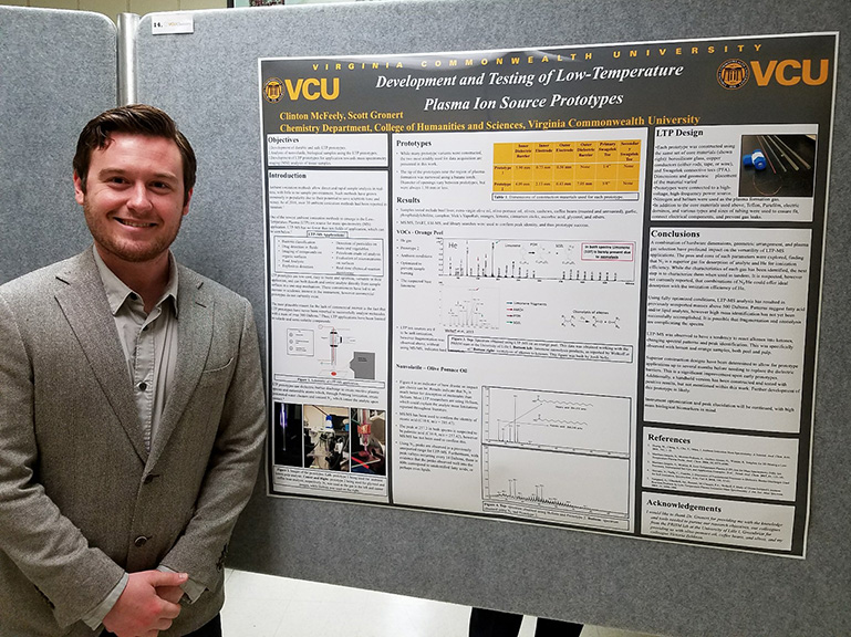 Clinton McFeely stands in front of a research poster hanging up on a bulletin board