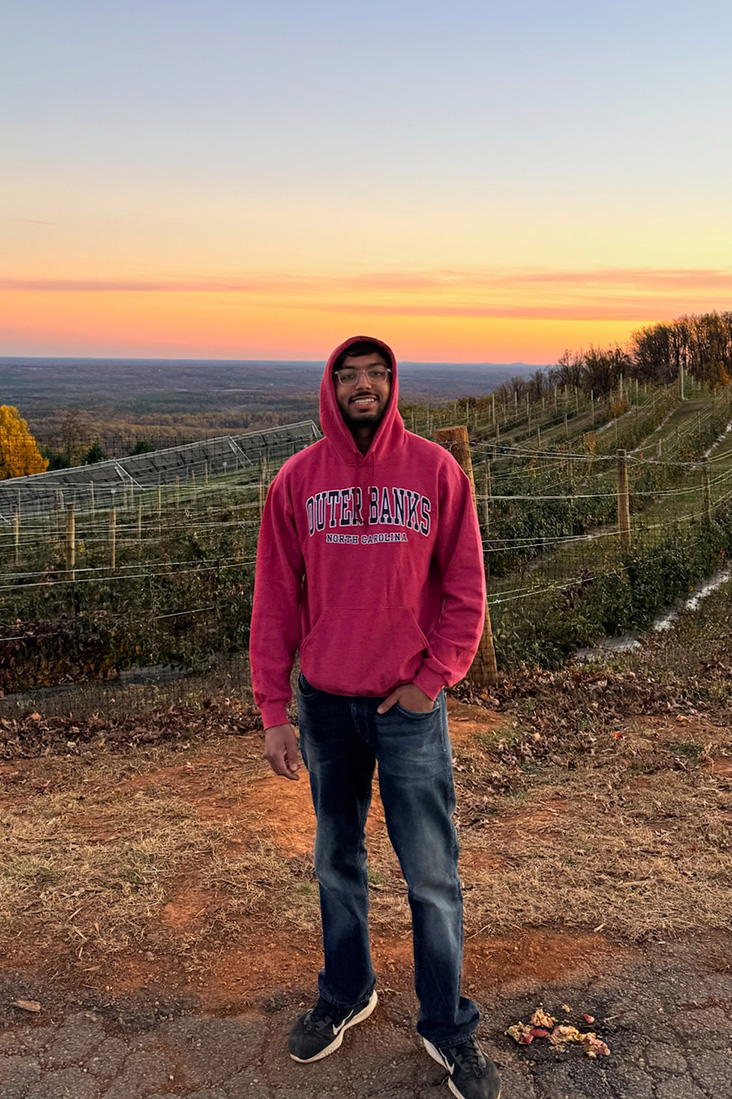 Rehan Adatia stands in front of a vinyard at sunset