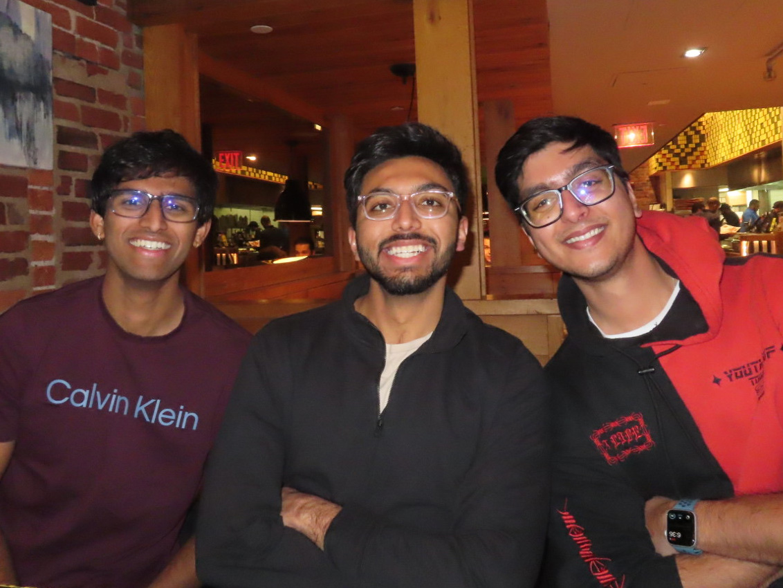 Rehan Adatia sits between two men at a restaurant